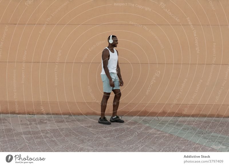 Schwarzer Sportler läuft beim Training auf der Straße Läufer Herz Aktivität Kopfhörer heiter Übung Motivation Fitness Mann Lifestyle Glück Gesundheit Lächeln