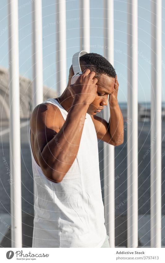 Schwarzer ernsthafter sportlicher Mann, der während des Trainings sein Smartphone benutzt Läufer Browsen benutzend Kopfhörer zuhören Athlet Pause Sportler