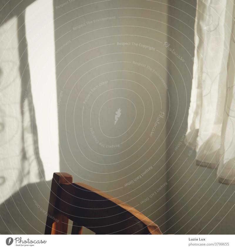 Licht und Schatten: Ein zarter Vorhang und sein Schatten an der Wand gegenüber, dazwischen ein altmodischer Stuhlrücken aus Holz Sonnenlicht Fenster Gardine