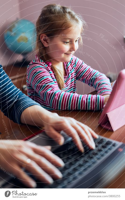 Mutter einer Frau, die während eines Video-Chat-Call-Stream-Online-Kurses auf einem Laptop von zu Hause aus ihren Job aus der Ferne erledigt, während ihre Tochter sich ein Video auf einem Tablet anschaut