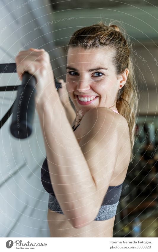 Junge glückliche Frau, die ihre Armmuskeln in der Turnhalle trainiert Fitness Übung Sport aktiv Lifestyle passen Fitnessstudio Sporthalle Gesundheit