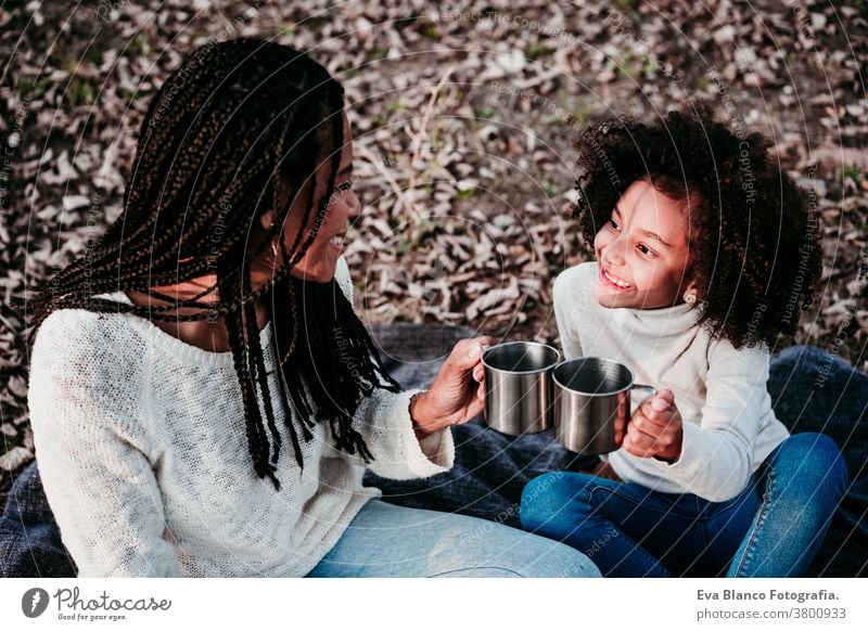hispanische Mutter und Afrokindermädchen picknicken im Freien und entspannen sich in der Natur. Herbstsaison. Familienkonzept Picknick Porträt Tochter