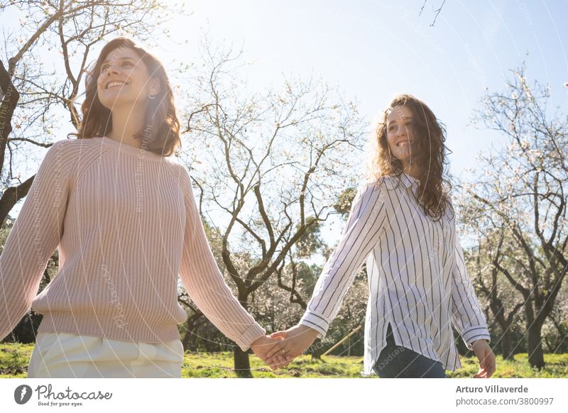 ein paar Mädchen gehen an einem sonnigen Tag Hand in Hand in einem Park spazieren. Sie laufen lächelnd und glücklich umher Aktivität Hintergrund schön hell