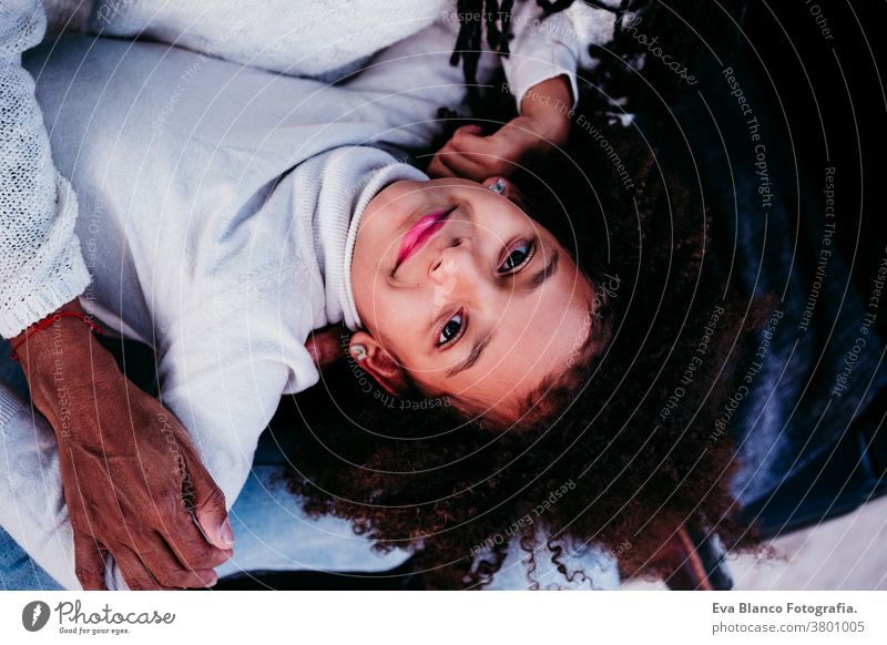 Draufsicht eines Afrokindermädchens mit ihrer Mutter im Freien, Herbstsaison, Familienkonzept Porträt Tochter gemischte Rasse hispanisch Afro-Look Mutterschaft