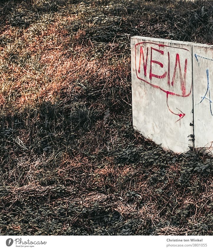 Das Wort "NEIN" mit roter Farbe geschrieben steht an einer niedrigen hellen Betonwand an einer Böschung Nein Graffiti Wand Mauer Schriftzeichen Fassade