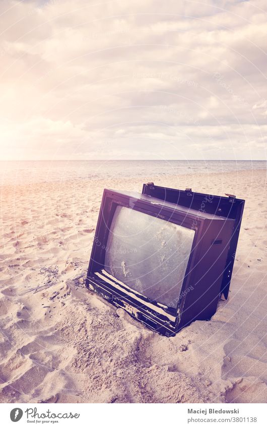 Alter kaputter Fernseher am Strand bei Sonnenuntergang. Fernsehen Sand gebrochen Bildschirm FERNSEHER veraltet Nachrichten Natur Technik & Technologie