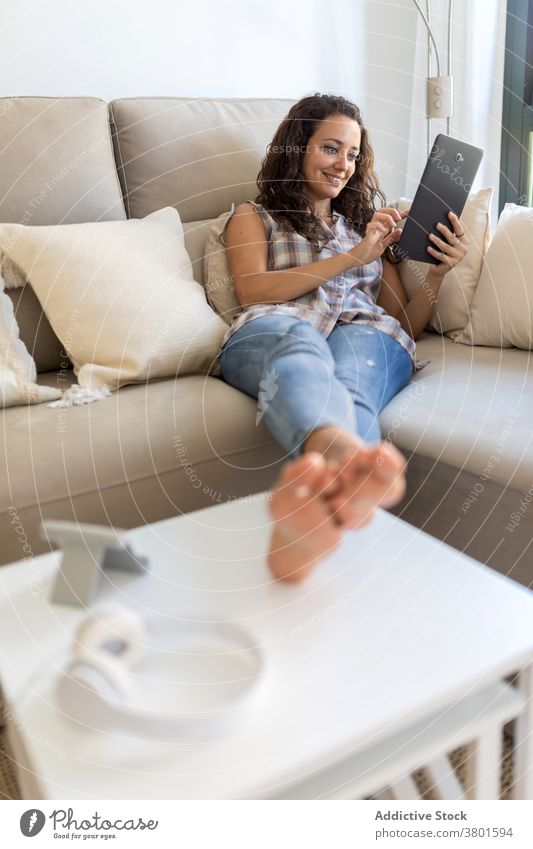 Fröhliche Frau, die im Wohnzimmer auf einem Tablet surft Browsen Tablette sich[Akk] entspannen heimwärts unterhalten benutzend Nachricht heimisch Wochenende