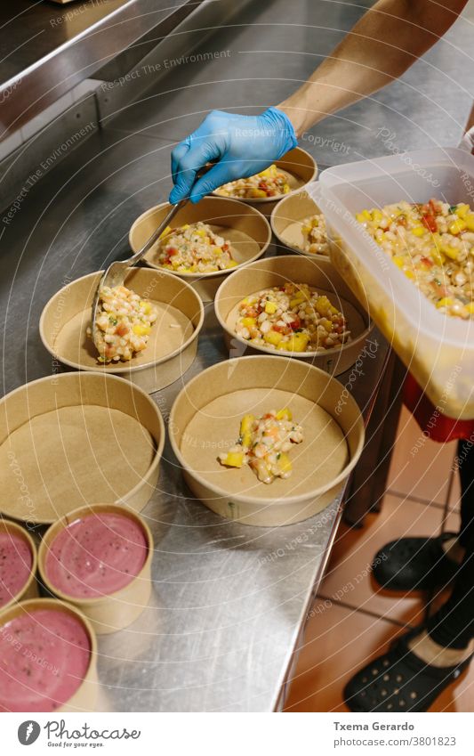 Koch bereitet Reissalate zum Mitnehmen vor. Die verwendeten Behälter sind kompostierbar. Essen zum Mitnehmen Salatbeilage Speiseeis Container Küche Hand Utensil