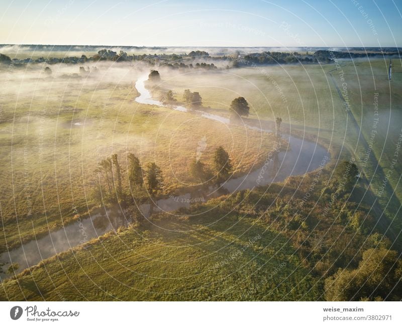 Luftaufnahme des Sonnenaufgangs im Herbst bei Nebel. Kleiner Fluss mit Bäumen in Wiese und Feld Natur Wasser Baum Antenne Wald Morgen Sonnenlicht Landschaft