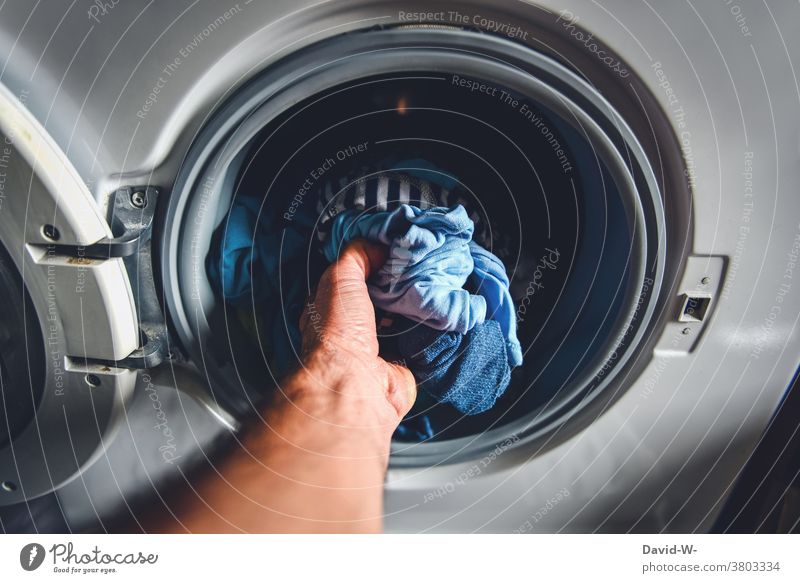 Mann macht Wäsche und greift in die Waschmaschine waschen Hausmann sauber Waschtag Haushaltsführung Wäsche waschen Alltagsfotografie Häusliches Leben Hand
