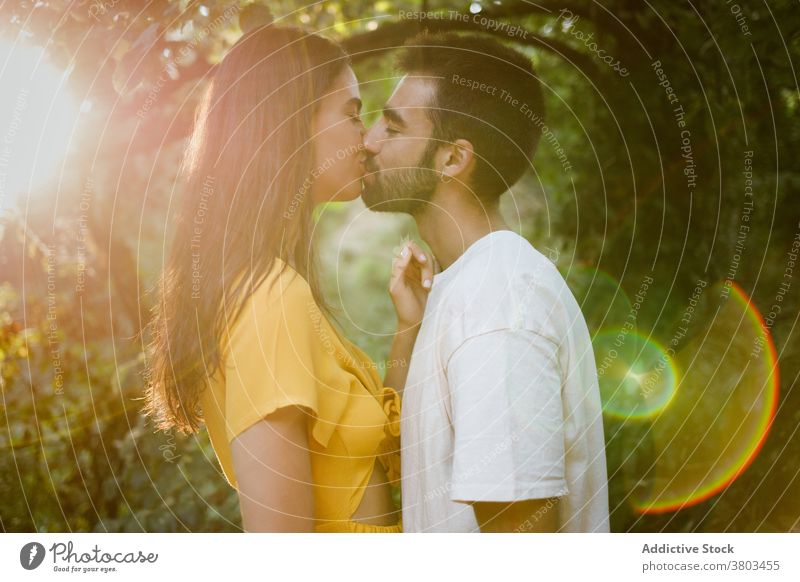 Glückliches ethnisches Paar, das sich im Wald küsst romantisch Termin & Datum Liebe Zusammensein ruhen Kuss Park Lächeln Partnerschaft sich[Akk] entspannen