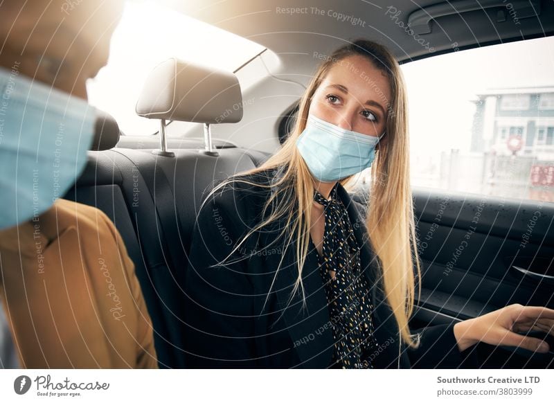 Masken tragendes Geschäftspaar unterhält sich während einer Gesundheitspandemie auf dem Rücksitz eines Taxis Business Geschäftsmann Geschäftsfrau Gesichtsmaske