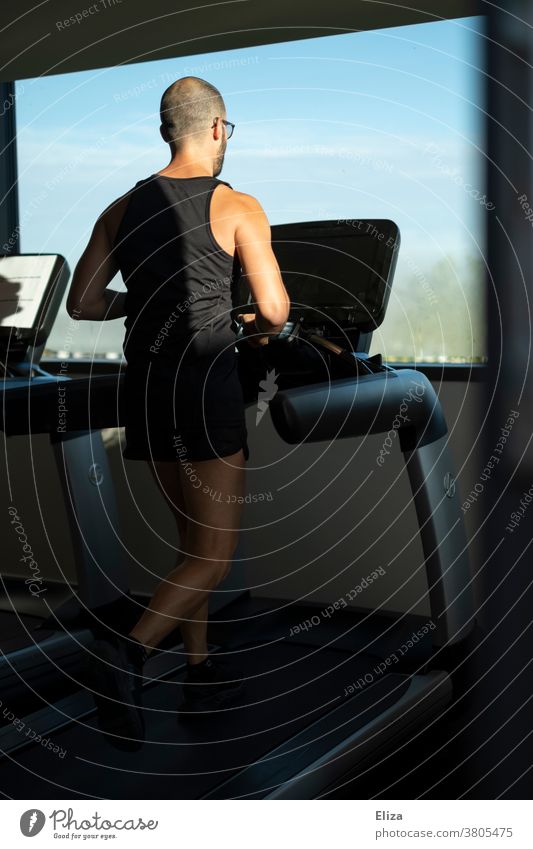 Mann trainiert auf einem Laufband mit Fensterblick im Fitnessstudio laufen Sonnenschein Sport Training Bewegung joggen drinnen Gerät Jogger Läufer laufend