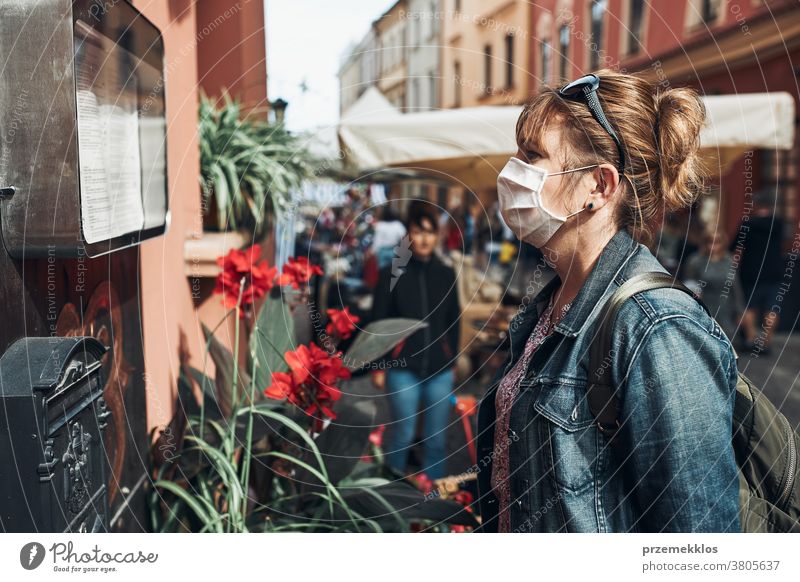Junge Frau, die auf einer Straße in der Innenstadt steht und zur Seite schaut und die Gesichtsmaske trägt, um eine Virusinfektion zu vermeiden Pflege Kaukasier