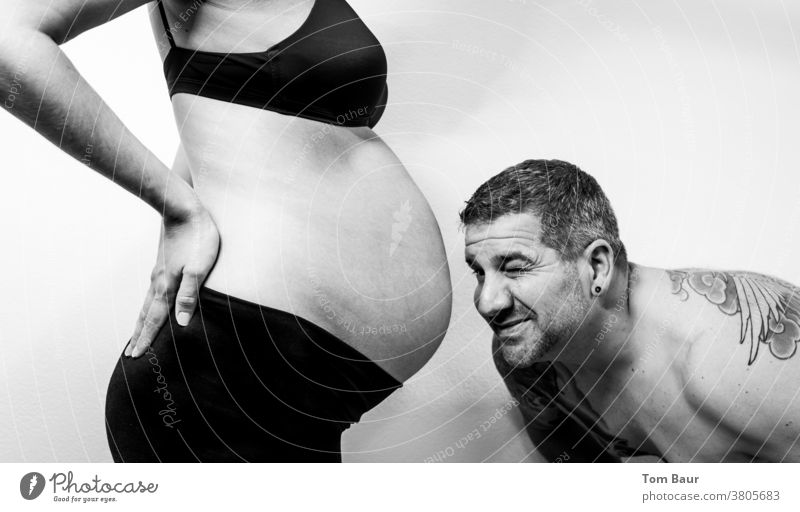 tätowierter Mann schaut in den Bauchnabel seiner im 9.Monat schwangeren Frau - Junge oder Mädchen? Babybauch feminin Erwachsene Farbfoto Mutter Mensch Hand