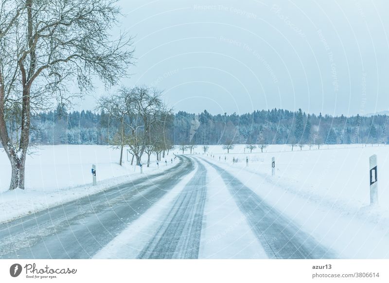 Einsamer, rutschiger, eisiger Winterstraßenverkehr mit weißer, schneebedeckter Spur. Die Strassenspur ist glatt gefroren. Hohe Unfallgefahr durch Schneesturm und heftiges Weihnachtswetter