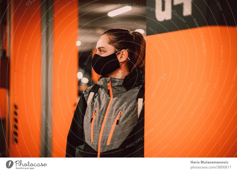 Frau mit Maske in der Garage an der orangefarbenen Wand Erwachsener attraktiv schön Schönheit schwarz lässig Sammlung cool Coronado-Brücke Coronavirus covid-19