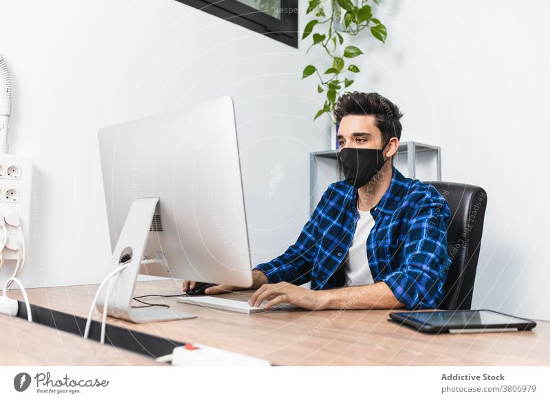 Anonymer Geschäftsmann in Maske tippt auf Computertastatur im Büro Unternehmer Tippen Arbeit Projekt Mundschutz Bund 19 Konzentration Desktop benutzend Gerät