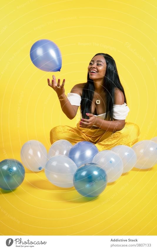 Fröhliche junge afroamerikanische Frau spielt mit Luftballons im Studio spielen Glück heiter Freude Stil Model Lächeln spielerisch positiv Optimist ethnisch