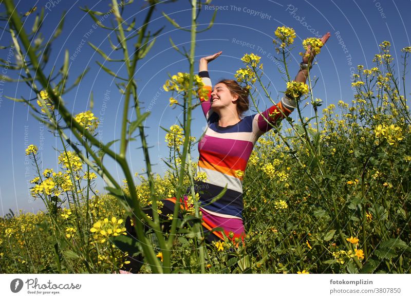 junge Frau springt mit erhobenen Armen in einem Rapsfeld Feld Optimismus Selbstvertrauen Lebensfreude Glück freuen sich freuen jauchzen strecken Lebenslust