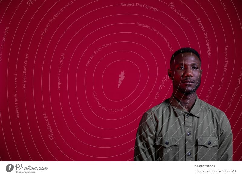 Junger schwarzer Mann posiert im Studio auf isoliertem roten Hintergrund Textfreiraum Porträt afrikanische ethnische Zugehörigkeit eine Person männlich