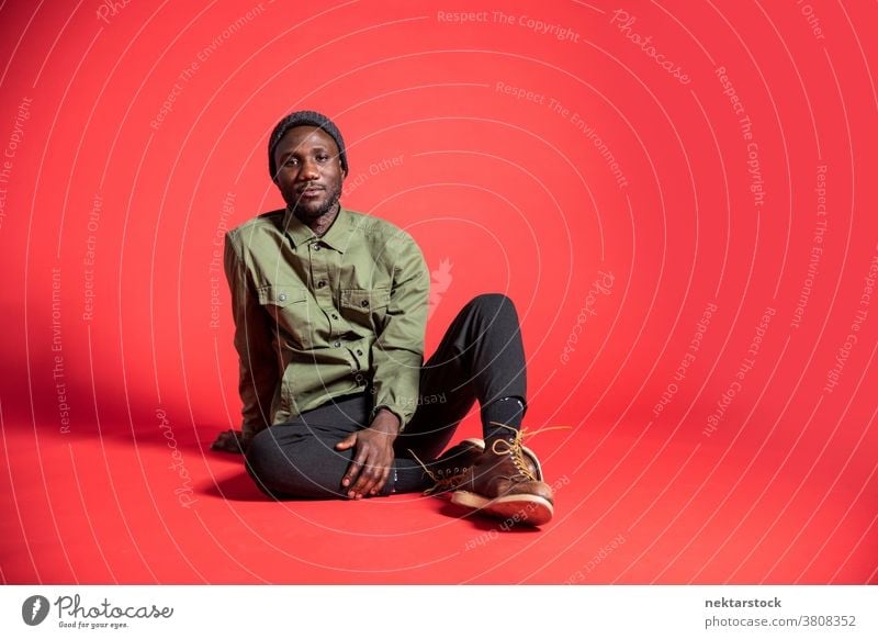 Junger schwarzer Mann posiert auf dem Studioboden sitzend Inhalt Pose afrikanische ethnische Zugehörigkeit eine Person männlich Nur ein Mann 20-30 Jahre alt