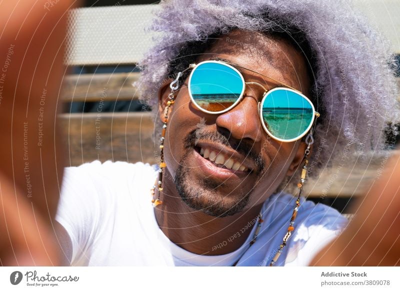 Schwarzer Mann mit Afro-Haar lächelnd und nehmen ein Selfie. Schwarzer Mann einen Selfie nehmend Afrohaar schwarz Lächeln Afrikanisch Amerikaner Afro-Look