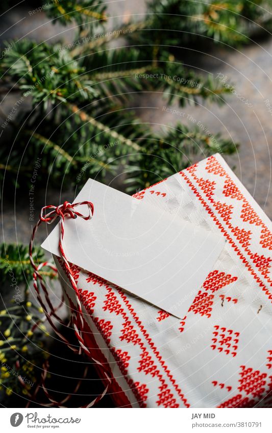 Verpackte Weihnachtsgeschenkschachtel, mit leerem Etikett und rotem Klebeband, umgeben von Kiefernzweigen auf grunge-blauem Hintergrund Kasten Geschenk Tag