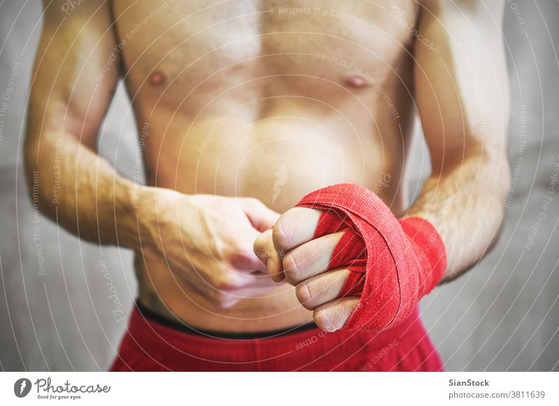 Der Mann umhüllt seine Hände mit roten Boxentüchern. Boxer Hand Wraps umhüllen Boxsport kämpfen Arme Hintergrund Handgelenk Athlet Kämpfer Fitness stark