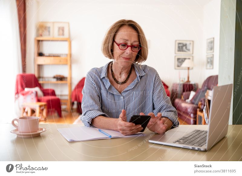 Senioren mittleren Alters, die zu Hause am Computer arbeiten Frau Laptop reif Menschen eine Telefon Smartphone Nachricht Talkrunde Person Lifestyle Schreibtisch