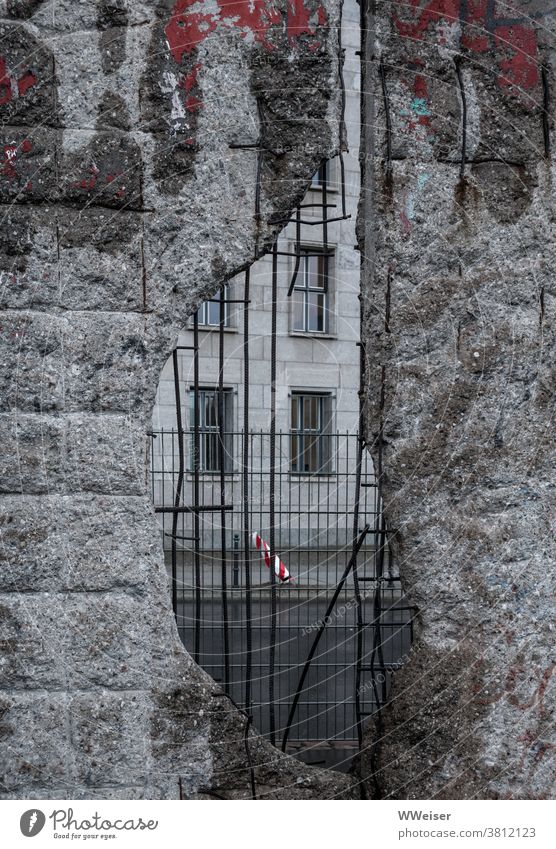 Durch das Loch in der Mauer sieht man bloß weitere Zäune und Wände, triste graue Welt Berliner Mauer Beton Stahlbeton Zaun Gitter Straße Schnellstraße Fassade