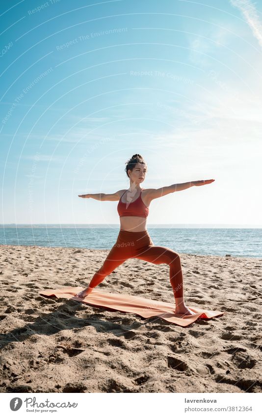 Junge erwachsene Frau praktiziert Yoga am Strand, Virabhadrasana II-Pose Übung Training MEER Gesundheit sportlich Aktivität Erholung Fitness Lifestyle friedlich