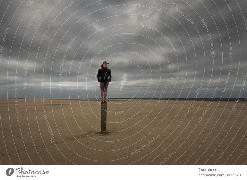 Aussichtsreich, Mann  steht auf einem Pfosten am Strand an einem bewölktem Tag Meer Küste Nordsee Himmel Horizont Personen Sandstrand Hozizont Wolken