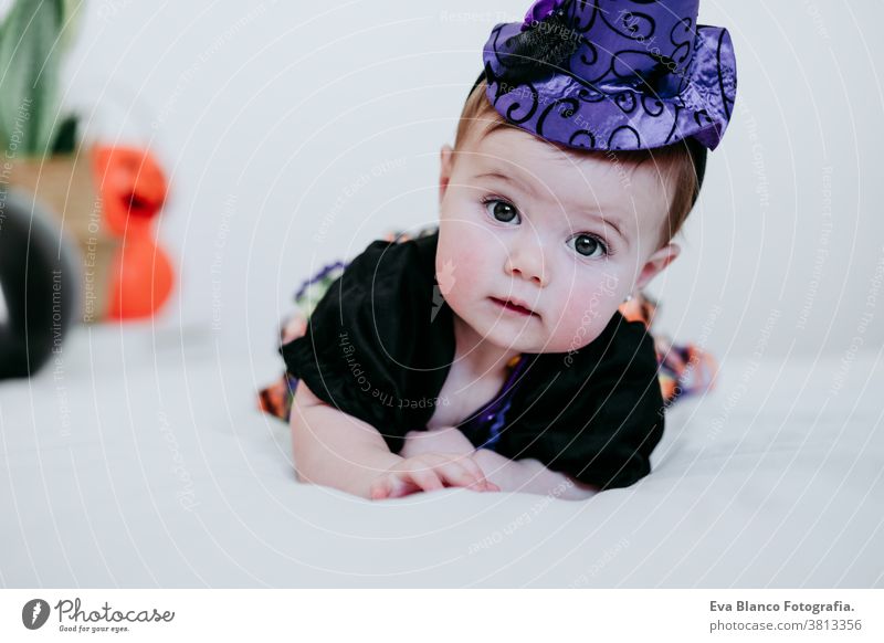 hübsches kleines Mädchen in Hexen-Halloween-Kostüm zu Hause, auf dem Bett sitzend mit Halloween-Dekoration, Lifestyle drinnen Tracht heimwärts im Innenbereich
