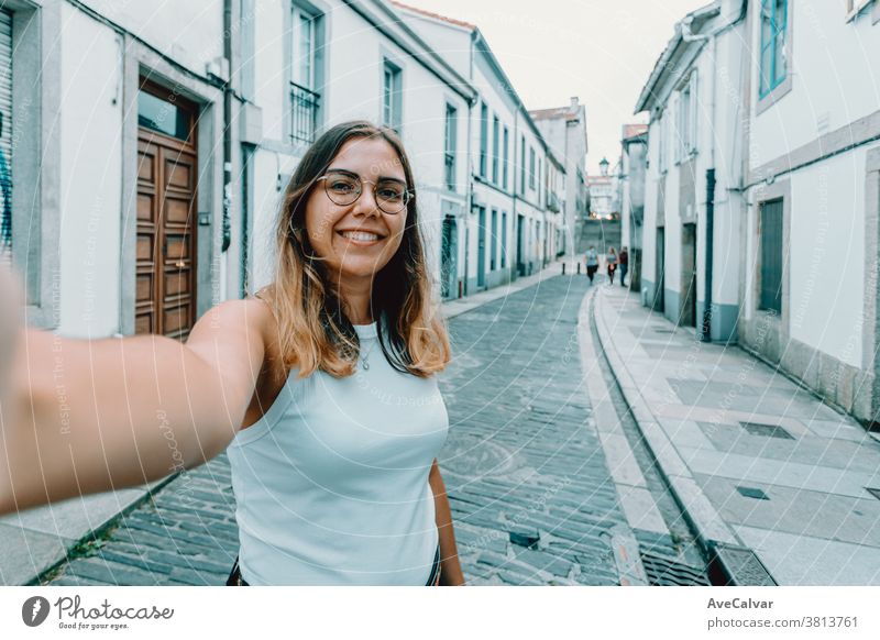 Junge Frau mit Brille bei einem Selbstmord auf einer alten spanischen Straße hübsch Smartphone trendy freudig brünett im Freien modern Schönheit Stil