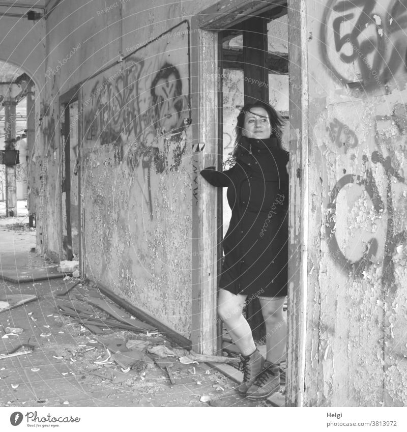 für bitti - langhaarige Frau im schwarzen Mantel steht in einer Türöffnung eines alten maroden Gebäudes Mensch Lost Place Wand Türrahmen Graffiti kaputt