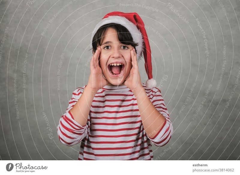 Frohe Weihnachten, schreiendes Kind mit Weihnachtsmannmütze Schrei schreit Heiligabend verrückt aufgeregt Ankündigung ankündigen positiv gestikulieren gestresst