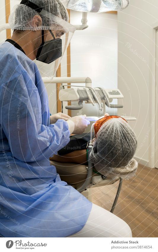 Zahnarzt behandelt Zähne eines Patienten mit UV-Licht ultraviolett Gerät Zahnmedizin Kur Stomatologie Werkzeug dental professionell Klinik Medizin mündlich