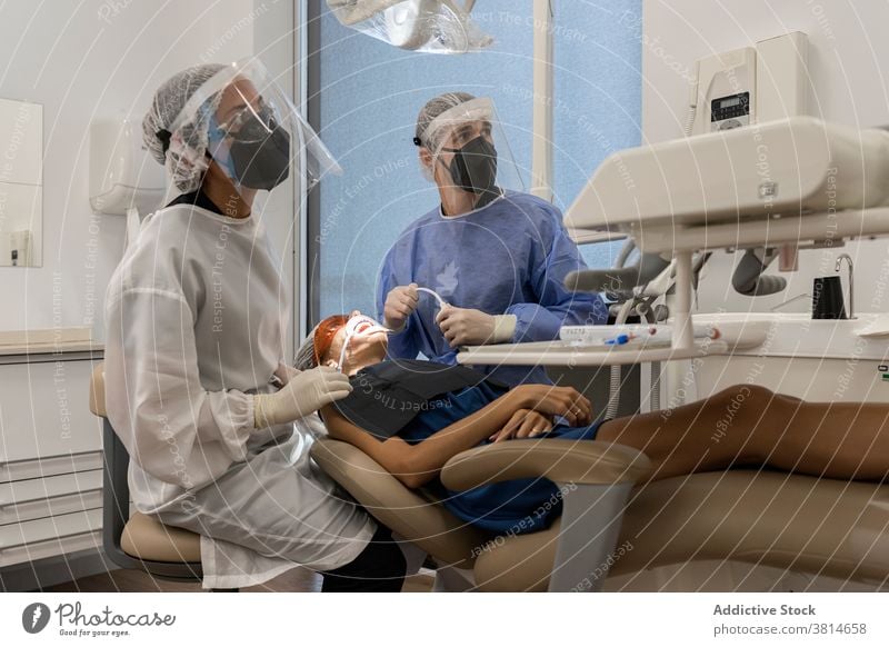 Zahnärzte mit Gesichtsschutz behandeln Patienten in der Klinik Zahnarzt Zahnmedizin Stomatologie Gerät geduldig Scan untersuchen Werkzeug Mundschutz