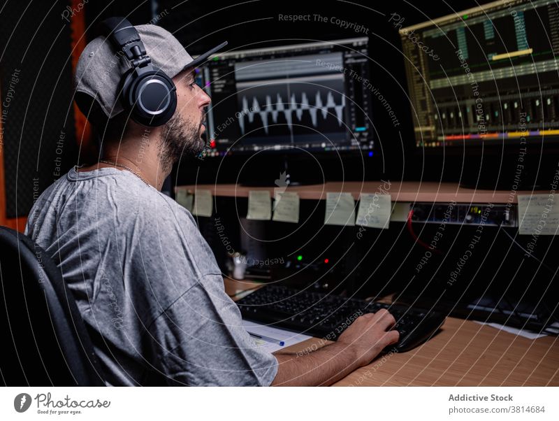 Mann im Musikaufnahmestudio mit verschiedenen Geräten Aufzeichnen Atelier Musiker männlich Tisch stereo Redner Monitor Anzeige Audio professionell Job Arbeit