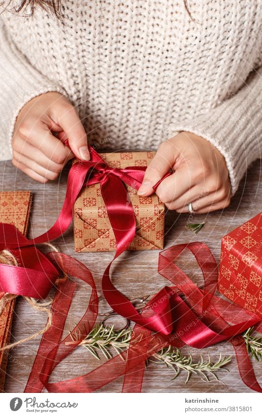 Frau bindet eine Bandschleife und packt Geschenke ein jemand Hände Krawatte Schleife Bändchen Papier abschließen Geschenkverpackung präsentieren Weihnachten