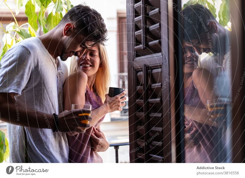 Verliebtes Paar umarmt auf Balkon am Morgen Liebe Partnerschaft Umarmen Glück Zusammensein trinken Zuneigung Umarmung jung heiter romantisch Freundin Lifestyle