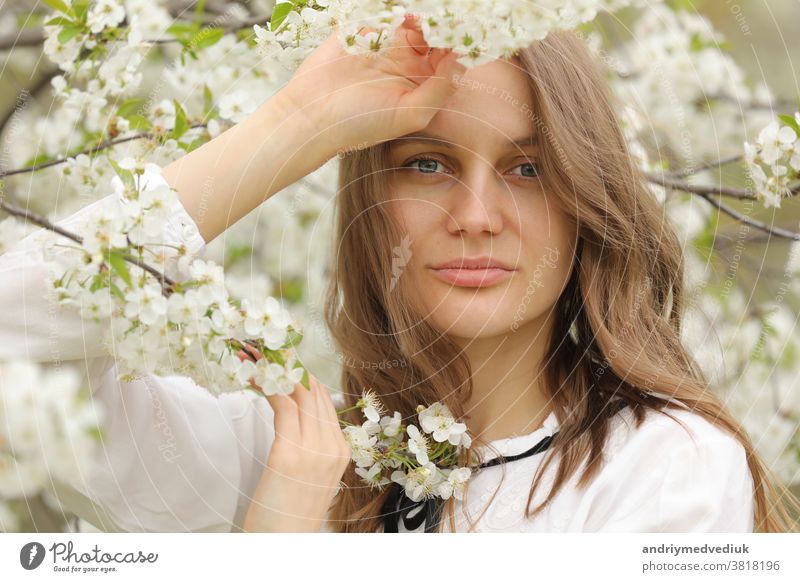 Porträt eines glücklichen Mädchens in Frühlingsblumen. Ein schönes junges Mädchen mit Blumenstrauss in der Nähe einer Blumenwand. Behaarung Wand geblümt Sommer