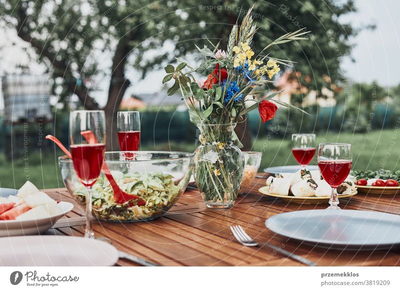 Abendessen in einem Apfelgarten auf einem Holztisch mit Salaten und Wein, dekoriert mit Blumen heimwärts Festessen Picknick Lebensmittel Sommer Barbecue Tisch