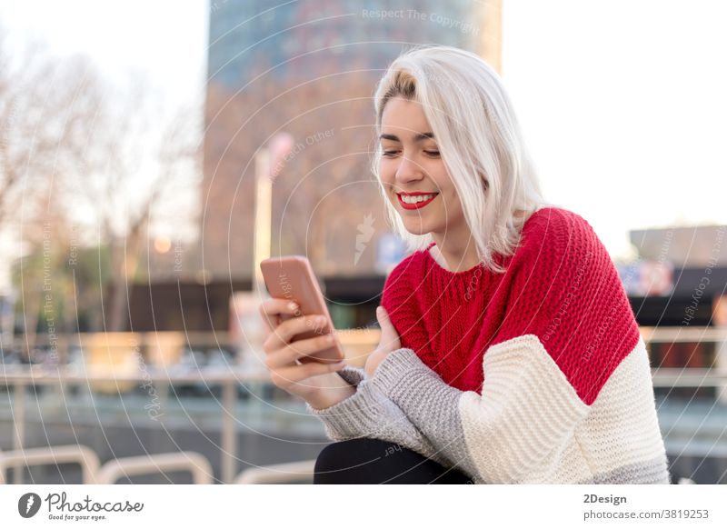 Nahaufnahme eines Porträts einer schönen jungen Frau, die ein Mobiltelefon im Freien in der Stadt benutzt Smartphone 1 Lächeln Beteiligung Fröhlichkeit Stehen
