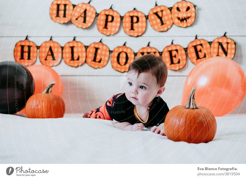 niedlichen Baby-Mädchen in halloween-Kostüm zu Hause, sitzen auf Bett mit Halloween-Dekoration, Lifestyle indoor kleines Mädchen Tracht heimwärts