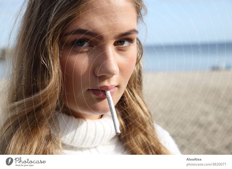 Blondes Mädchen steht am Ostessestrand und hat eine selbstgedrehte Zigarette im Mund Landschaft Strand intensiv jugendlich freundlich Natur weiblich einzigartig