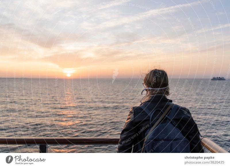 Frau mit Mund-nasen-schutz schaut auf Meer mund-nasen-schutz reisen Mundschutz Pandemie Sonnenuntergang Maske Corona Infektionsgefahr Corona-Virus COVID