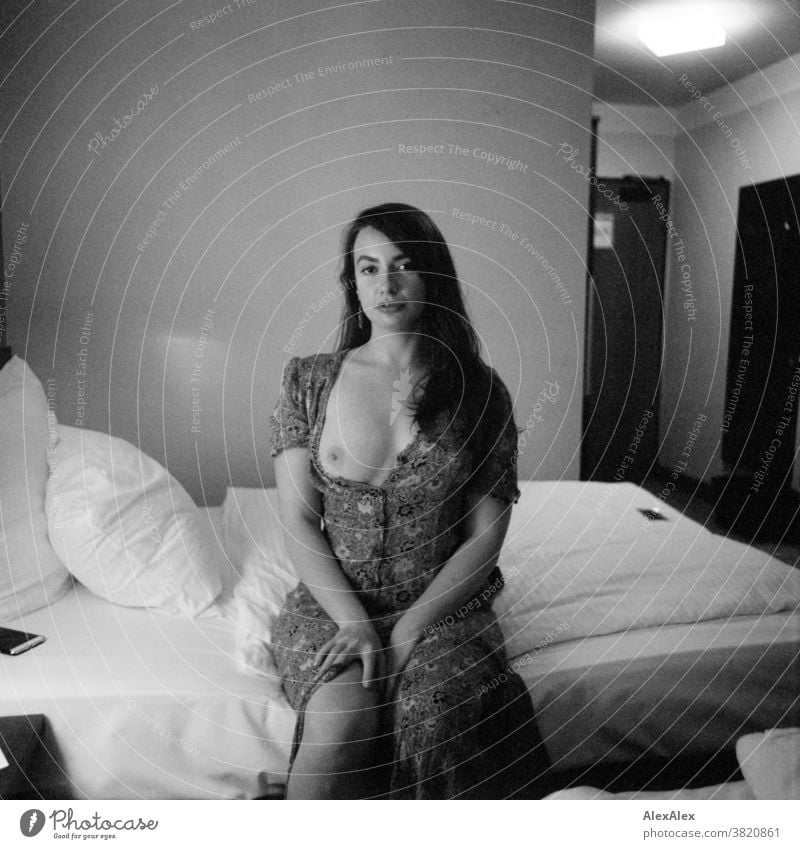 Portrait einer jungen Frau, die auf einem Hotelbett sitzt klassisch wild Sommerkleid Kleid Dekolleté Jugendliche Raum Zimmer Blick in die Kamera lange Haare