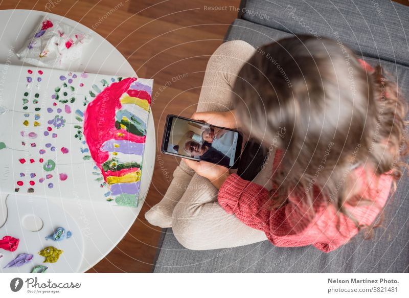 Little Kid hält ein Smartphone in der Hand, während sie sich mit ihrem Großvater am Handy unterhält. Gruß lustig Spaß Skype Pflege Anruf sprechend Glück Hallo